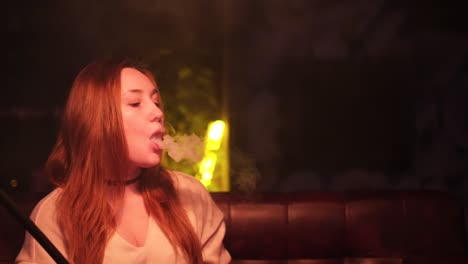 mujer fumando narguile en un club nocturno