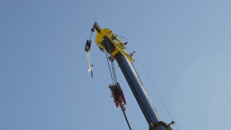 low angle shot of junkyard crane deloaded, isolated against clear blue sky