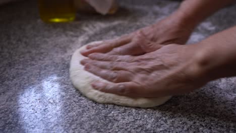 chef kneading homemade pastry dough on flour work surface, closeup