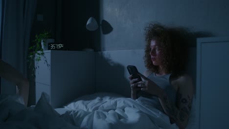 woman using a smartphone in bed at night