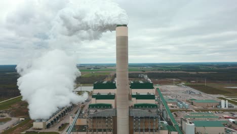 a shot rising up slowy showing the full height of a large illinois power plant smoke stack. large plumes of steam can be seen coming out.