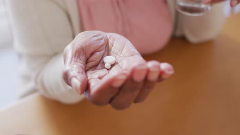 Mujer-Afroamericana-Mayor-Sentada-En-La-Mesa,-Tomando-Pastillas