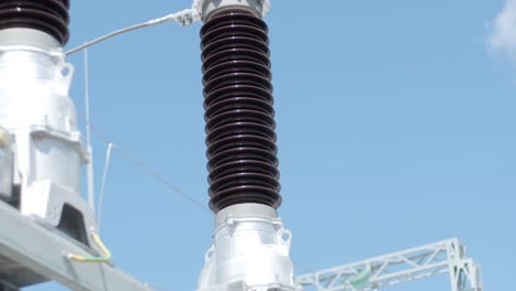 many high voltage electrical insulators in power substation against blue sky background