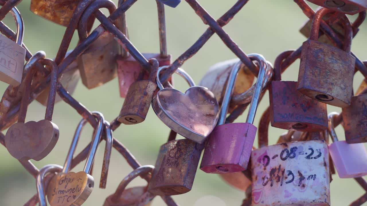 Close up view of Love locks in a fence in Montmartre Paris backlit by the sun during summer daylight.