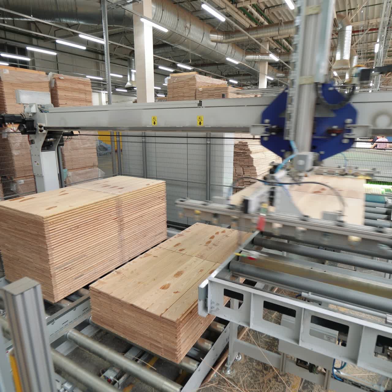 Manufacture of flooring, parquet processing. Modern factory equipment. Robots working at industrial factory.
