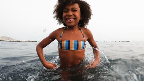 afican child having fun throwing sea water in front of camera during vacation time