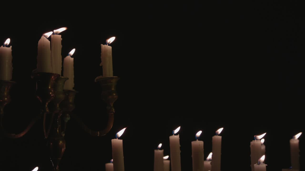 un grupo de velas blancas, algunas en un candelabro, encendidas y funcionando durante un tiempo