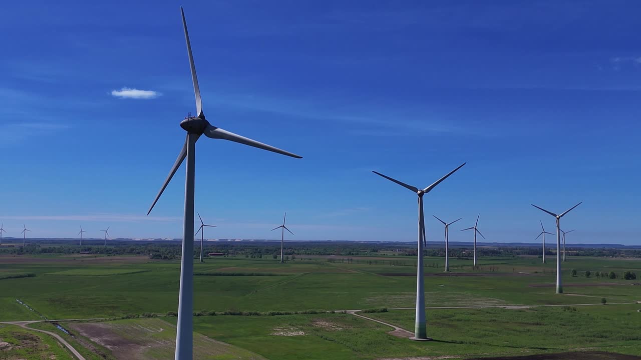 Wind turbines spinning on a sunny day over a vast green field