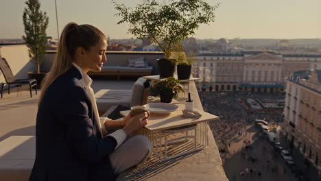woman enjoying coffee on a rooftop balcony with a panoramic city view at golden hour