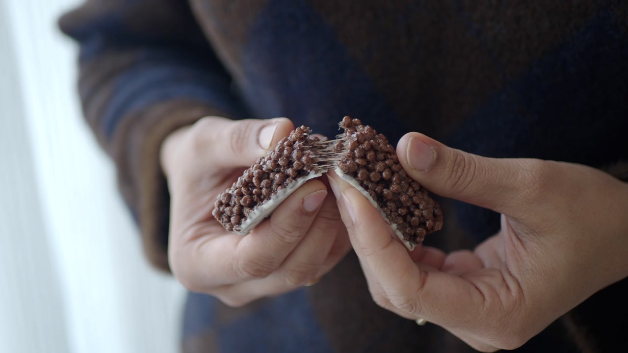 Close-up of Hands Breaking a Gooey Chocolate Snack Bar
