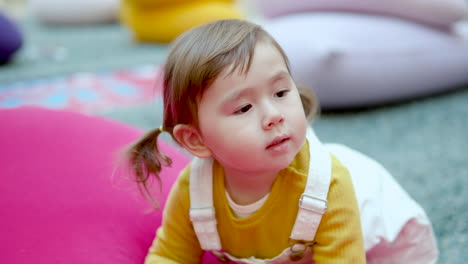 cute 3-year-old toddler girl looking at something in a play area inside a shopping mall