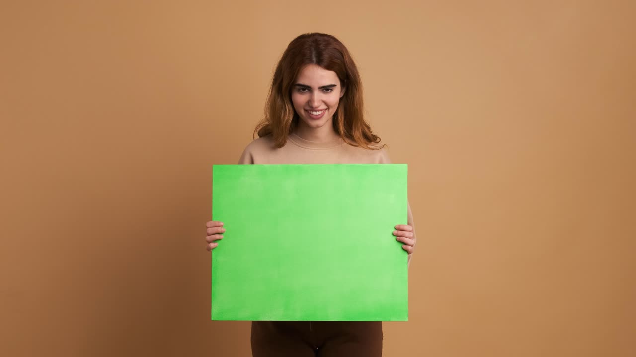 Smiling young woman holding a green board