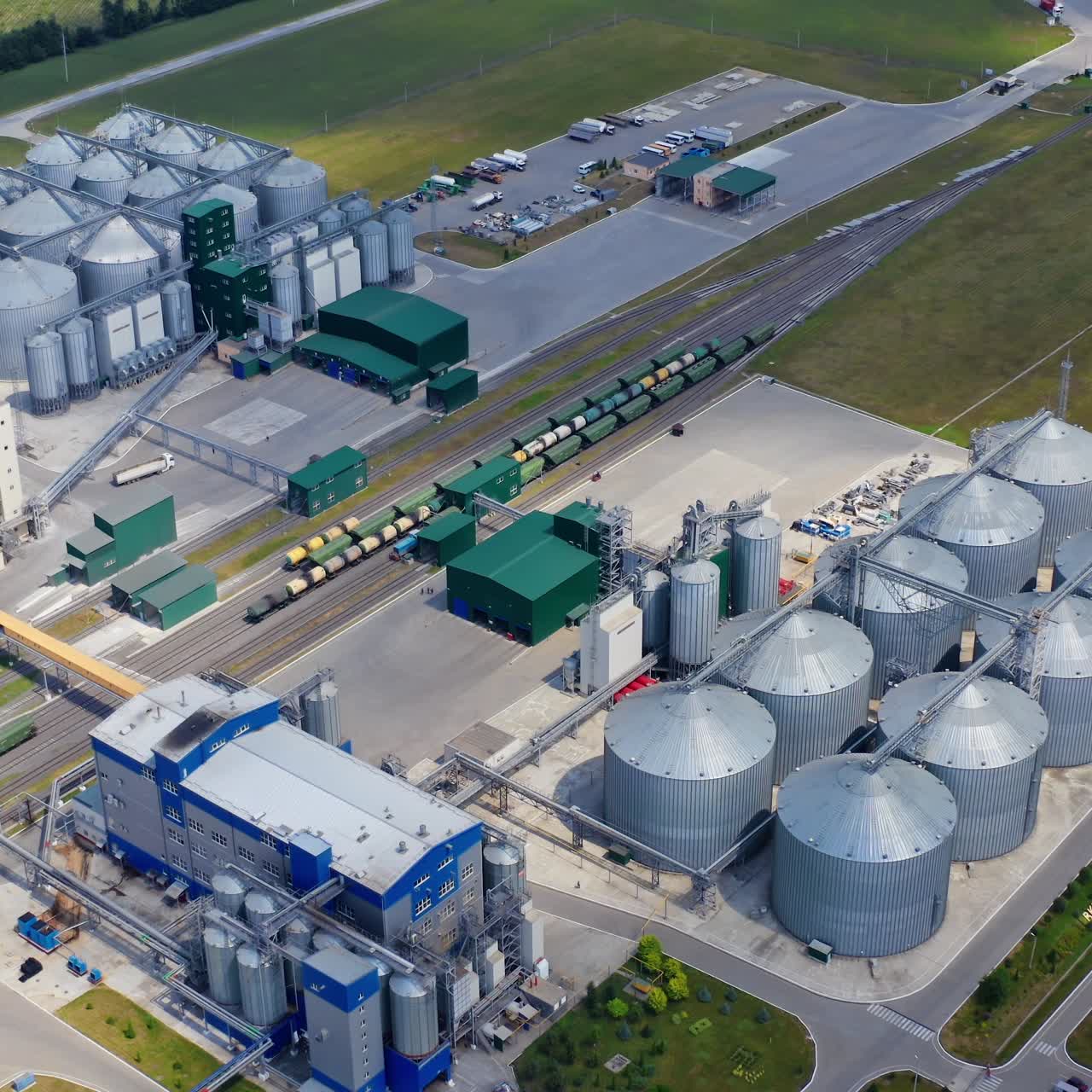 Agricultural processing plant. Modern factory with large silver grain elevators. New industry on field. Top aerial view