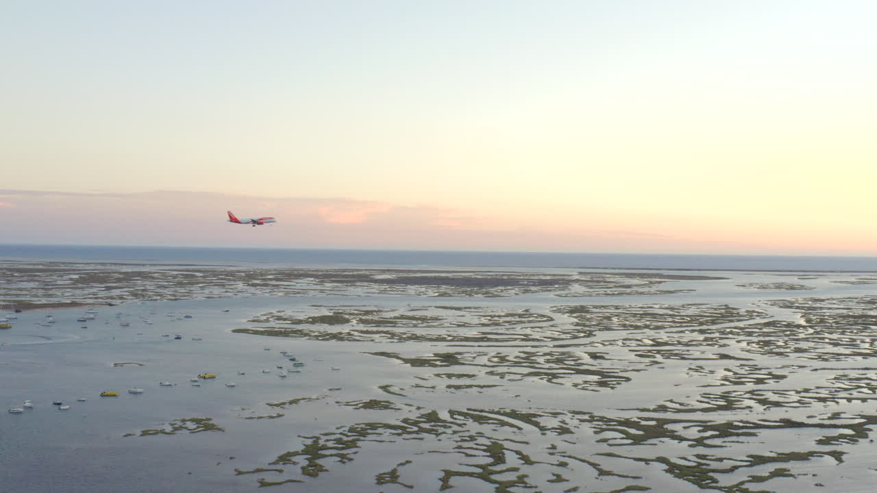 Passagerfly lander over Ria Formosa-lagunen i Faro Algarve ved solnedgang