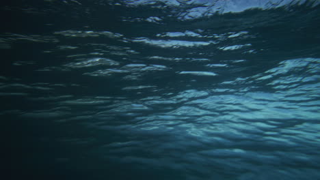 rear view from behind of thick textured ocean water surface as it crashes into wave, slow motion