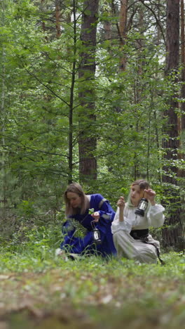 niñas con linternas en las manos recogen hierbas medicinales y plantas en el bosque joven, hierba