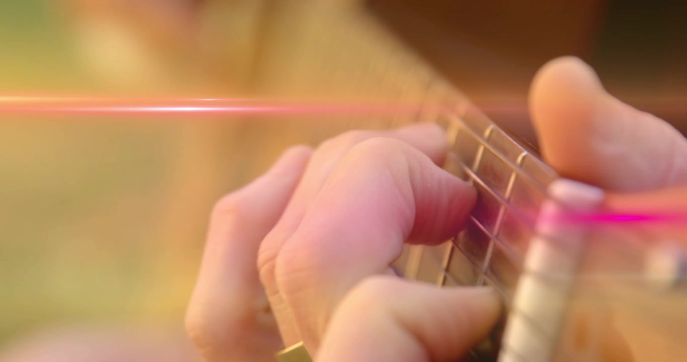 Guitarist with taped thumb picking and fretting, causing moving tabs over pink flare for music demo