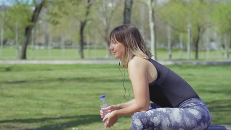 Mujer-Joven-Sonriente-Descansando-Después-Del-Entrenamiento-Y-Escuchando-Música.