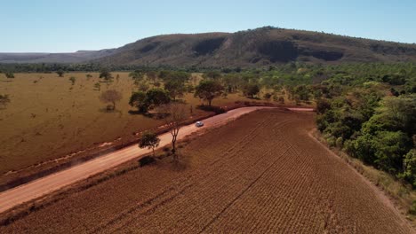 drone view of a moving car raising dust on a dirt road in chapada dos veadeiros, goiás, brazil