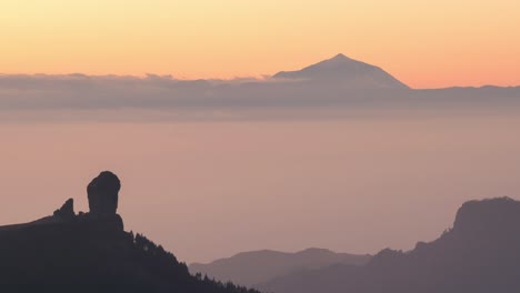 stunning sunset timelapse of roque nublo and teide emerging from the mist. golden sky, mountain silhouettes, and tranquil vibes. perfect for travel, nature, adventure, and scenic projects