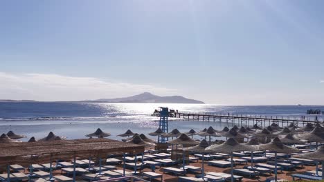 muchos paraguas de paja en una playa de arena cerca del mar rojo, vacaciones en la playa.