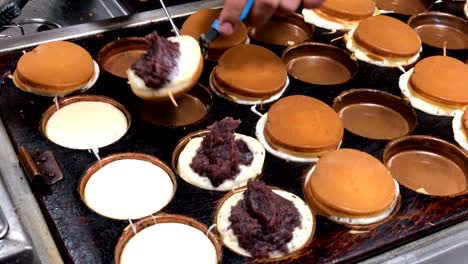 making delicious obanyaki or imagawayaki by drop the young bread into a hot pan stuffed with cream custard and other. traditional japanese snack is popular.