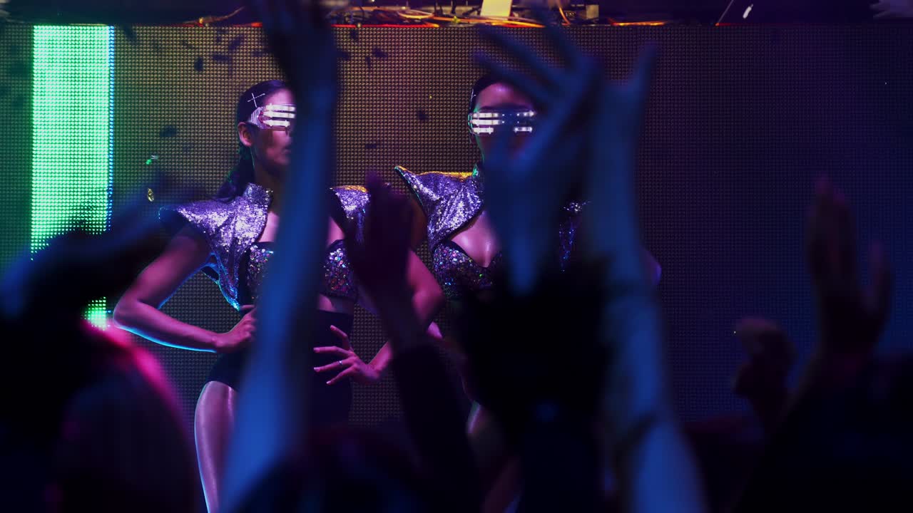 Bir grup insan diskoda, gece kulübünde sahnede DJ'in müziğiyle dans ediyor
