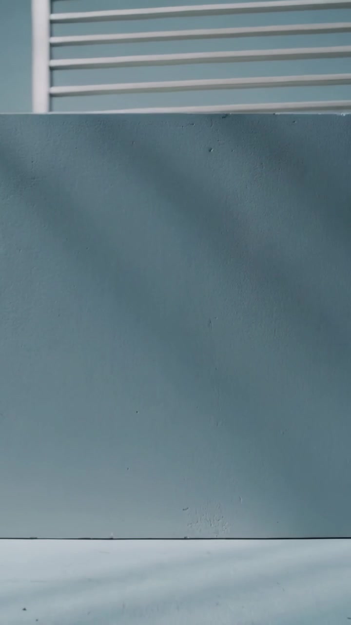 Vertical video: Tilting camera revealing wall and slatted railing on balcony to show fading shadows