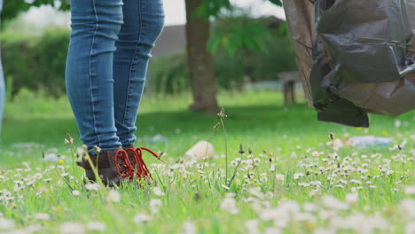 primer plano de mujeres voluntarias recogiendo basura y máscaras de ppe desechadas en el campo