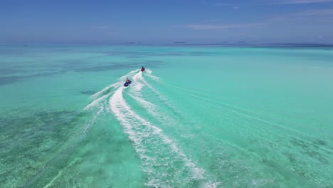 drone following jetskis driving in turquoise waters of the maldives, sunny day