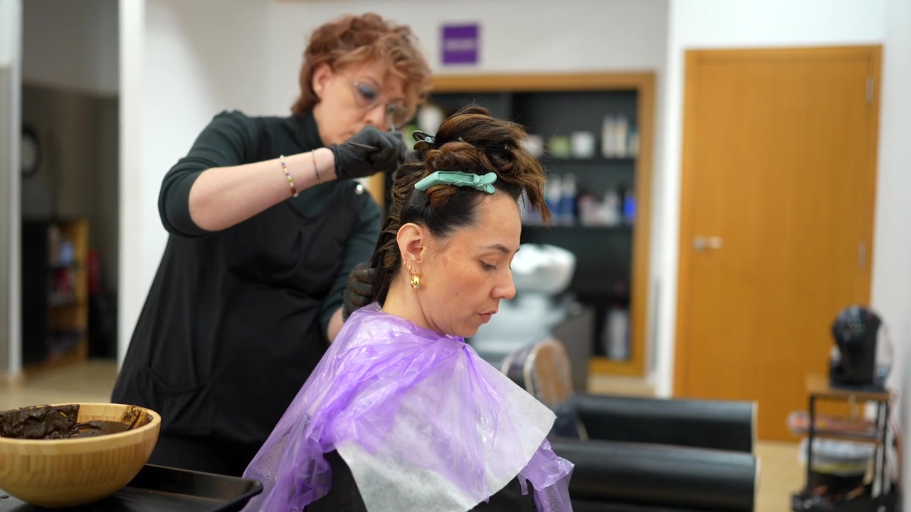 Cabeleireiro profissional aplicando tintura de cabelo na cliente no salão