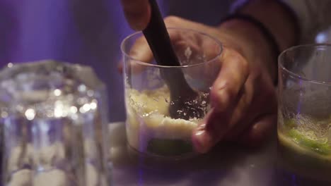 barman preparing drink with mint, yellow sugar and lime in a bar