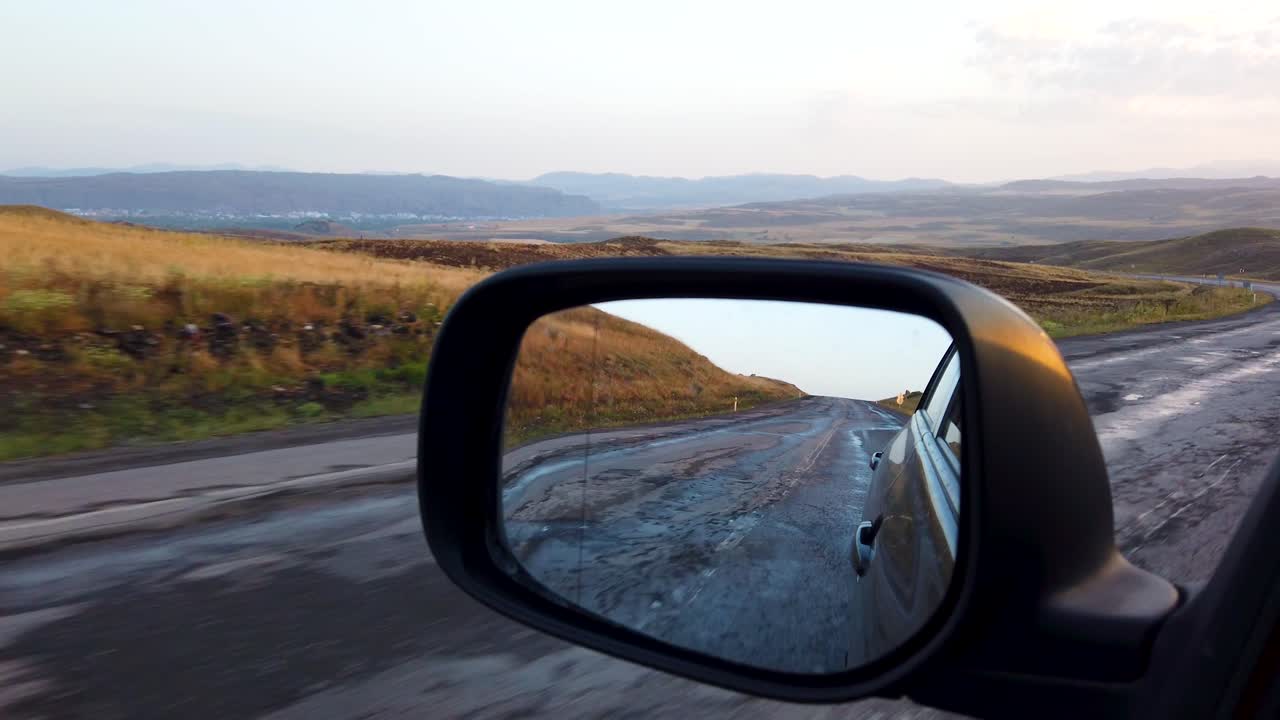 Reflection side rear view car mirror in the morning on the road at sunset or sunrise