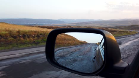 reflection side rear view car mirror in the morning on the road at sunset or sunrise