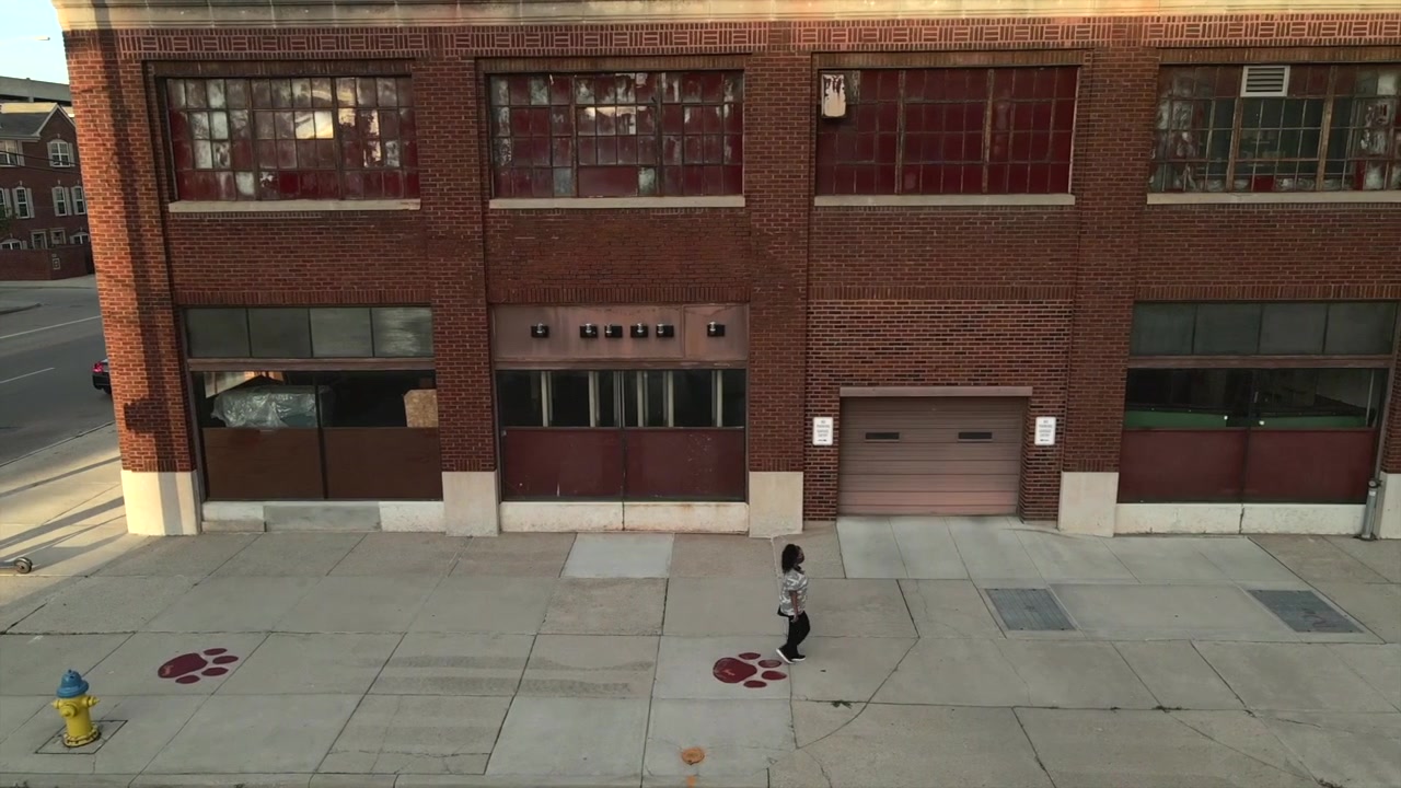 Woman walking past an abandoned building.