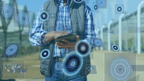 Animation-Des-Scannens-Von-Zielfernrohren-Und-Der-Datenverarbeitung-Auf-Bildschirmen-über-Einem-Mann,-Der-Ein-Tablet-Verwendet