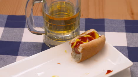 perro caliente medio comido y un vaso de cerveza