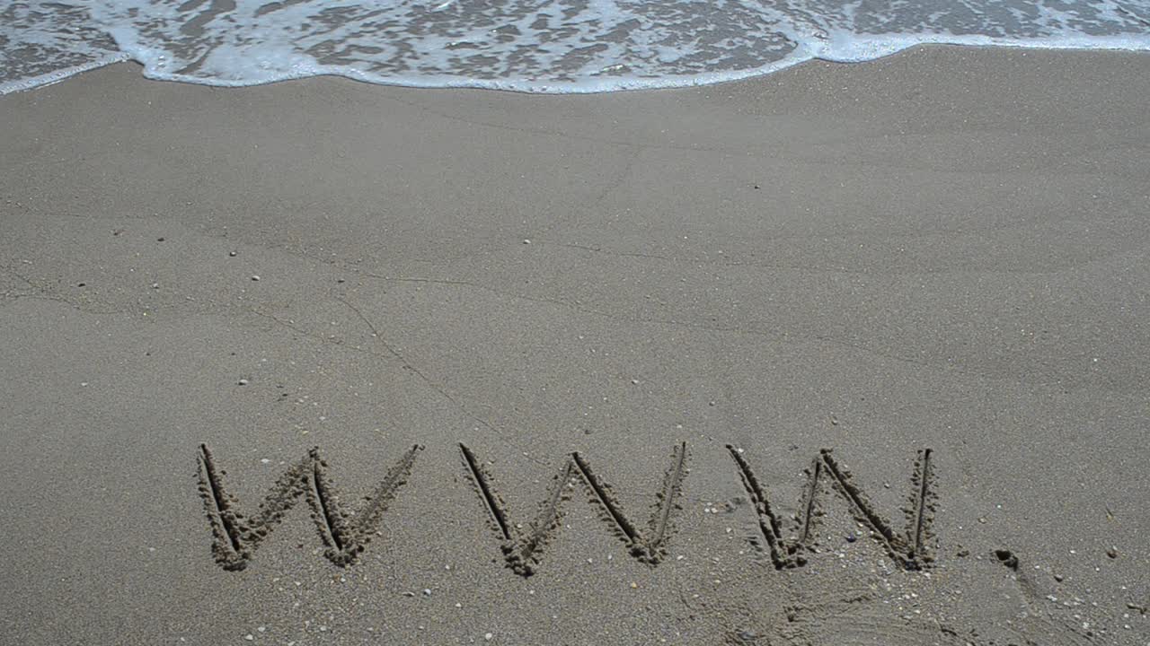 Ordet www håndskrevet i sand på en strand. Optagelse på stranden.