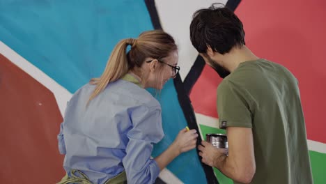 smiling couple paints on canvas drawing picture in art studio making fun with brush