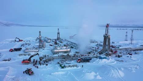 drilling operations in a snowy landscape: heavy machinery and workers engaged in energy production in a icy environment under a pale sky