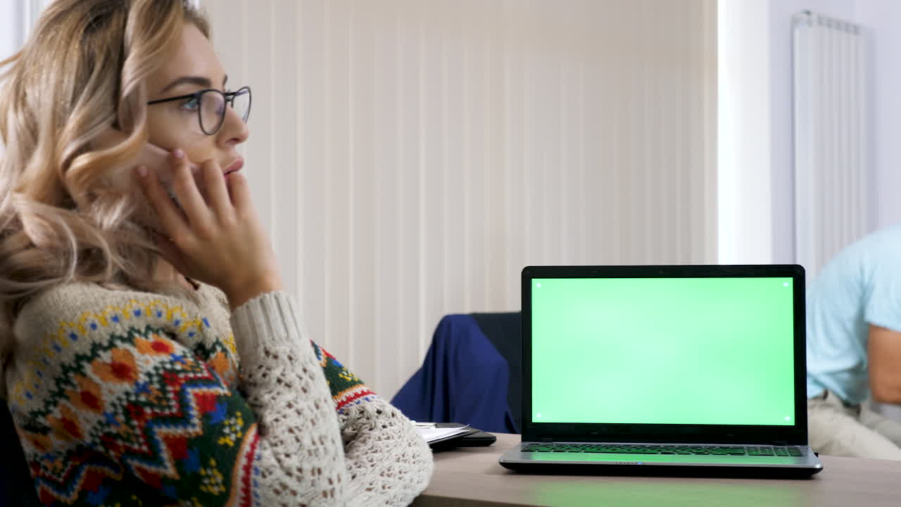 Man playing video games at home office with a laptop and a green screen