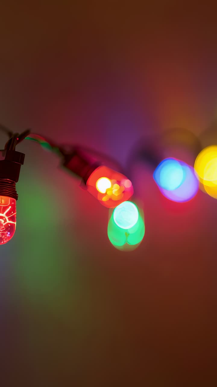 Vertical video: Shifting camera focus revealing colorful string lights on warm tan wall, with bokeh