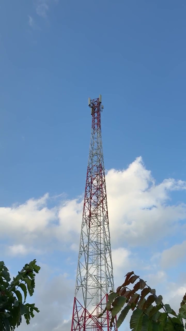 Torre di telecomunicazioni contro un cielo blu con nuvole.