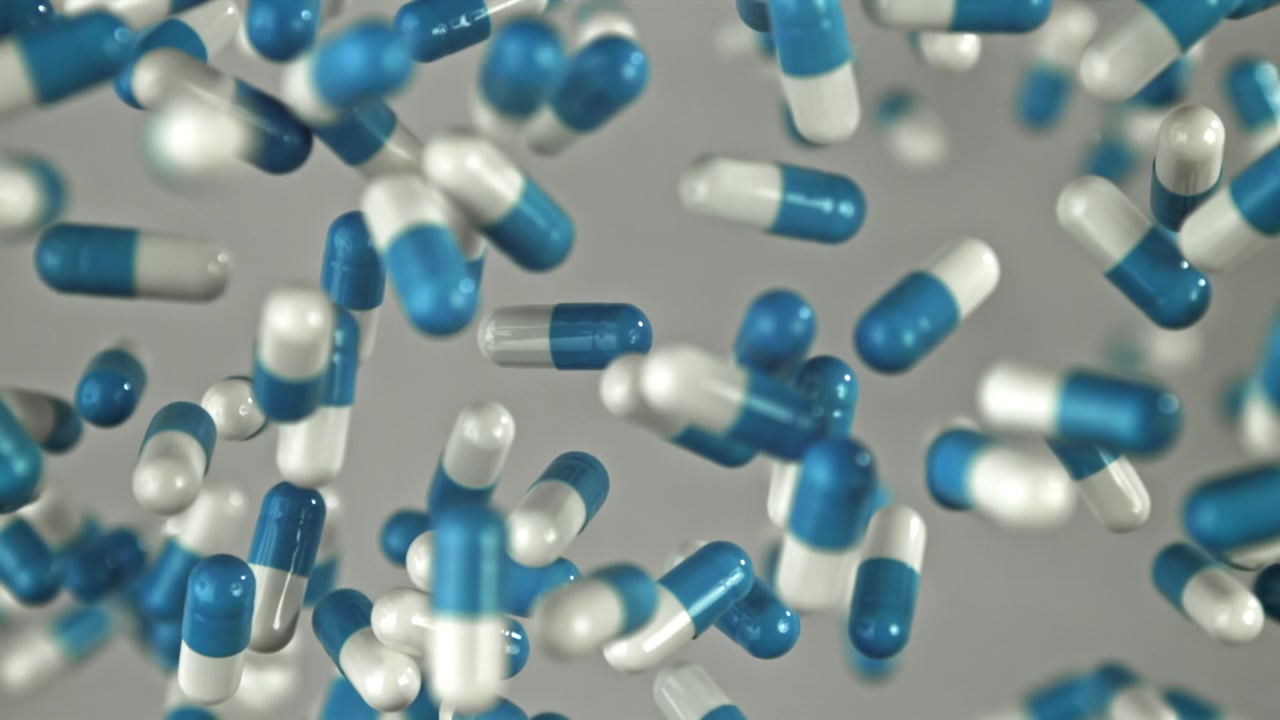 Capsule farmaceutiche blu e bianche che cadono al rallentatore