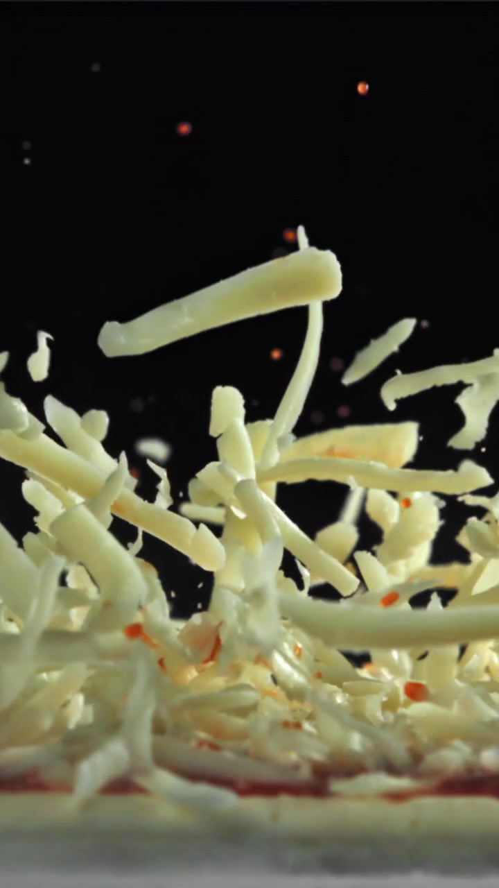 Mozzarella grattugiata che cade su una base per pizza al rallentatore