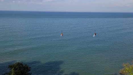 batumi botanical garden zip line where 2 friends ride together on background we can see black sea with oil tankers