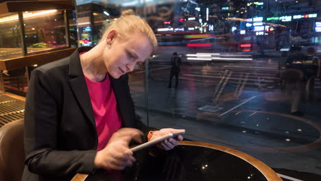 Zeitrafferaufnahme-Einer-Frau,-Die-Im-Café-Sitzt-Und-Ein-Touchpad-Auf-Dem-Hintergrund-Der-Stadt-Seoul,-Südkorea,-Verwendet