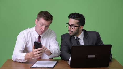 dos jóvenes empresarios multiétnicos trabajando juntos contra un fondo verde