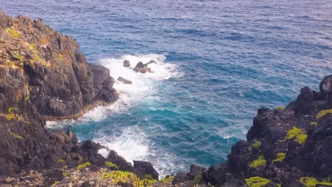 CLIFF-over-caribbean-sea,-seen-from-the-top-of-the-mountain,-tilt-down-splash-water,-Gran-Roque