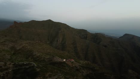 Luftflug-über-Serpentinenstraße-Hinter-Bergen,-Die-Mit-Grünem-Wald-Bedeckt-Sind.-Zick-Zack-kurvenreiche-Asphaltschlangenstraße-Am-Hang-Mit